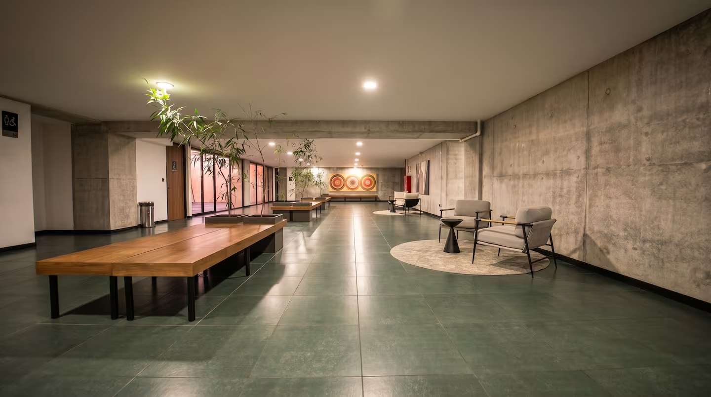 Interior hallway at Art Haus Tower with concrete walls, wood benches, and seating areas